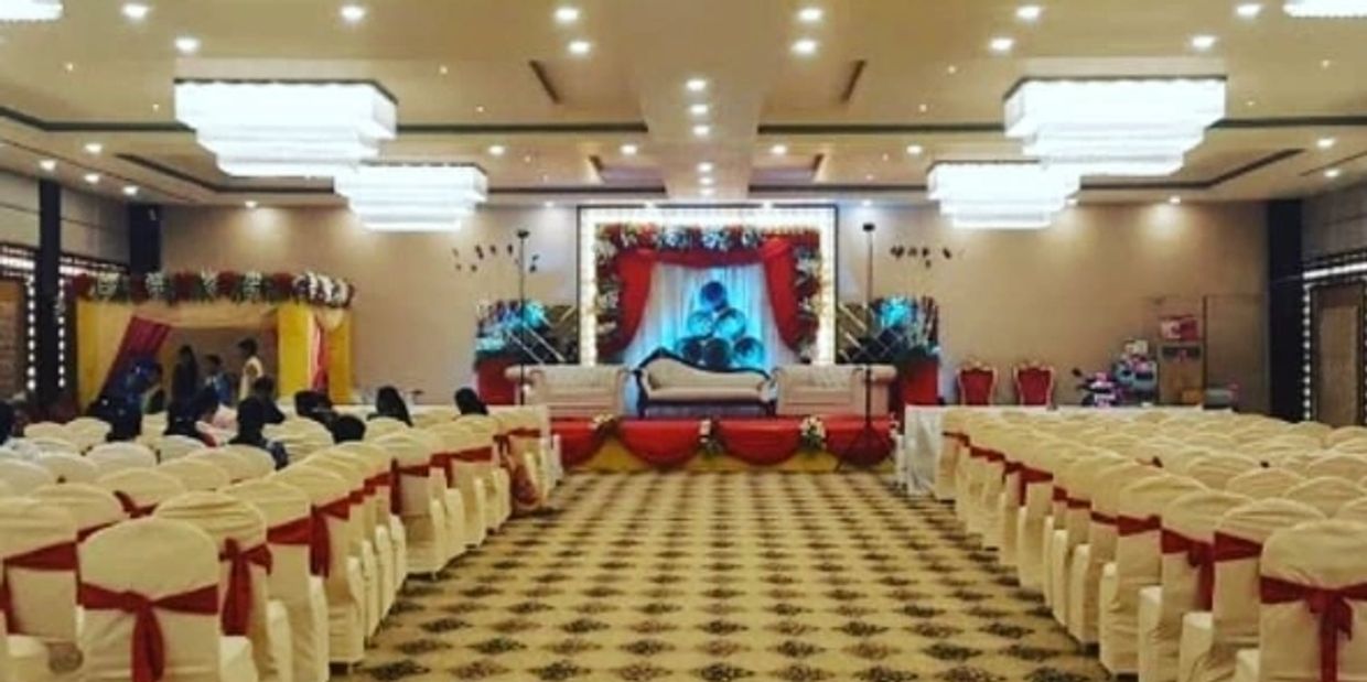 Decorated wedding hall with seating and stage.