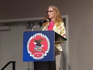 Becky standing behind a podium, getting ready to speak at the NRA-ILA State Conference.