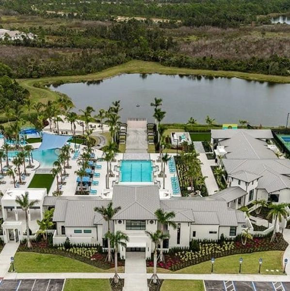 Aerial view of a modern resort with pools, palm trees, and a lake in the background.