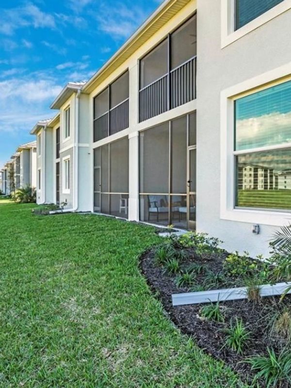 Modern apartment complex with screened balconies and well-maintained lawn.