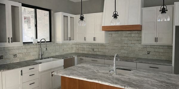 Modern kitchen with marble countertops and white cabinetry.