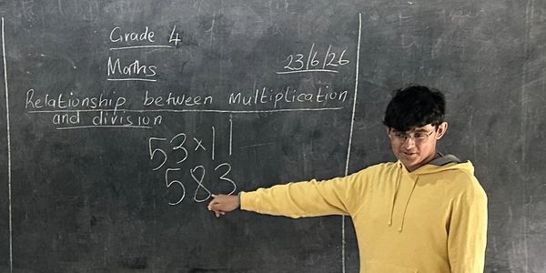 Student explaining multiplication and division on a blackboard.