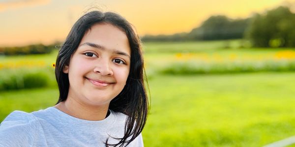 Smiling girl in a green field at sunset.