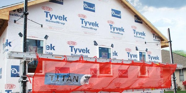 Under-construction house with Tyvek HomeWrap and a red Titan safety net scaffold.
