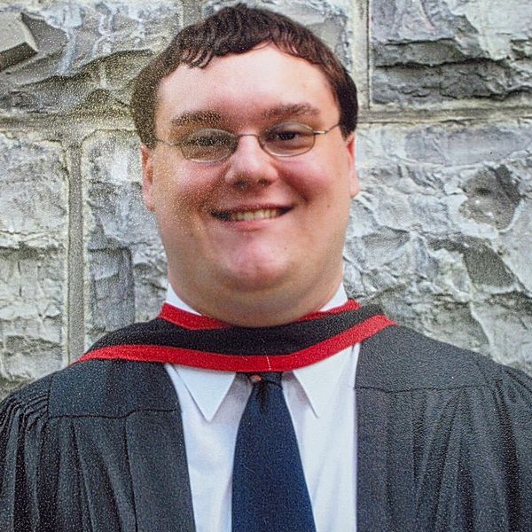 Young man in graduation attire smiling.