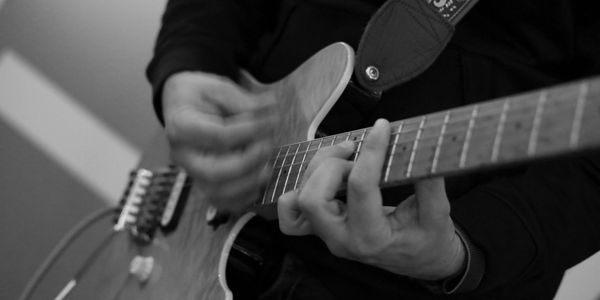 Black and white close-up of hands playing an electric guitar.
