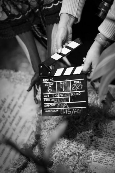 Hands holding a clapperboard on a film set in black and white.