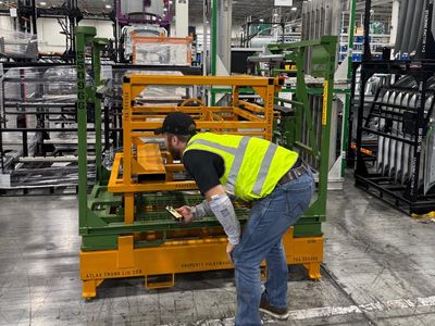 Worker inspecting industrial equipment in a factory setting.