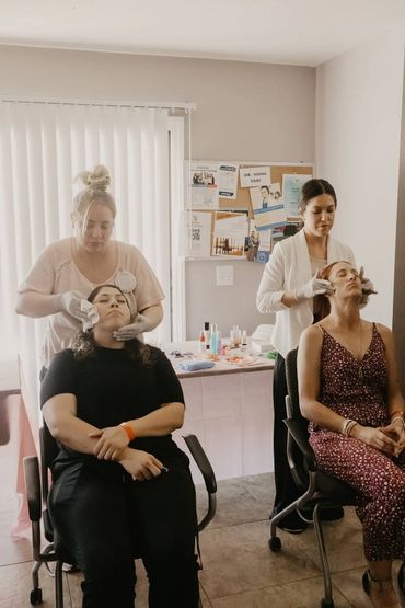 Two women receiving facial treatments from professionals in a serene room.
