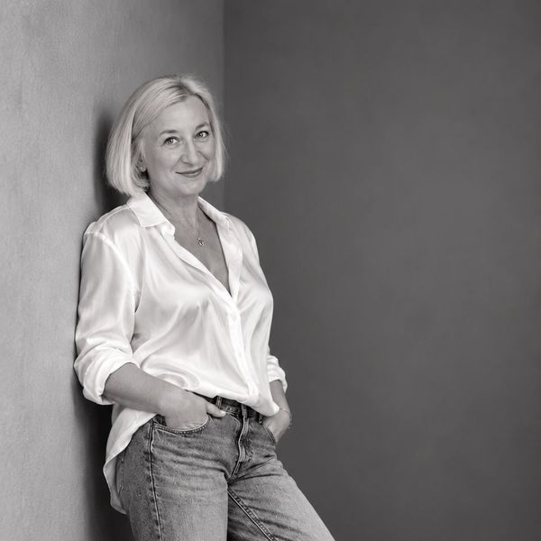Woman leaning against a wall, smiling.