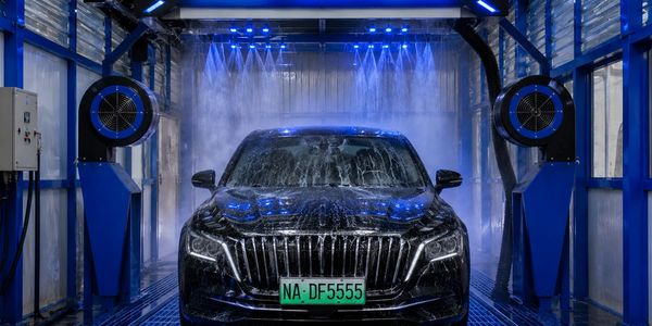 A black car undergoing a wash with blue lights.