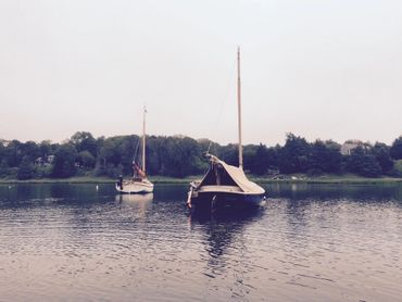 Two cat boats on their moorings in Frost Fish Cove, Orleans MA on Cape Cod