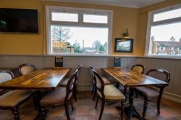 Cozy dining room with wooden tables and chairs near large windows.