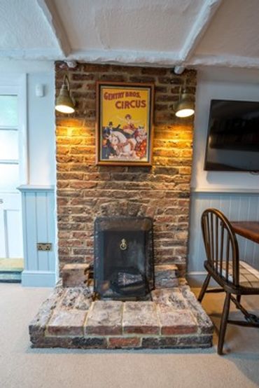 Cozy brick fireplace with vintage circus poster and warm lighting.
