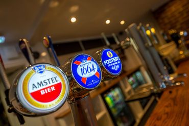 Beer taps for Amstel, Kronenbourg 1664, and Foster's in a bar.