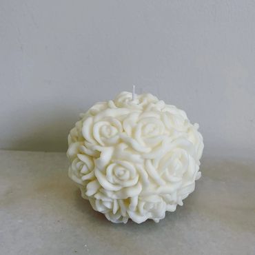 White spherical candle adorned with intricate rose patterns.