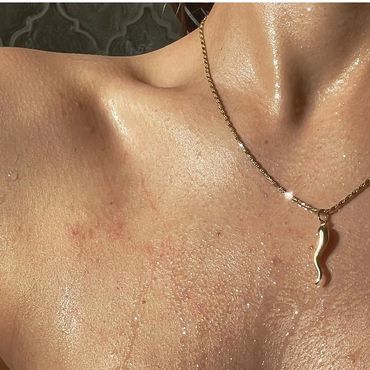 Close-up of a sunlit collarbone and neck with a gold necklace.