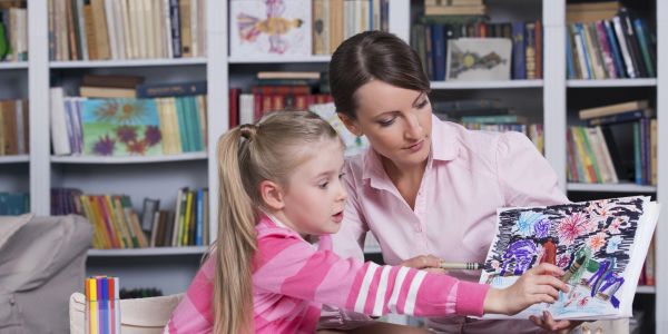 Woman and girl discussing a colorful drawing.