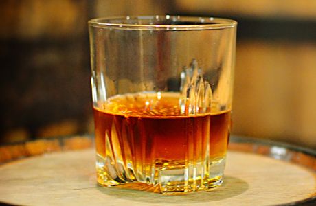 whiskey in glass tumbler on whiskey barrels