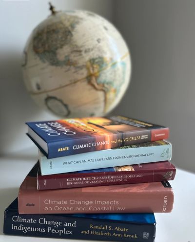 Stack of climate change law books with a globe in background.