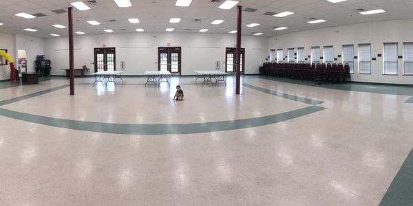 A large empty hall with a child sitting in the center.
