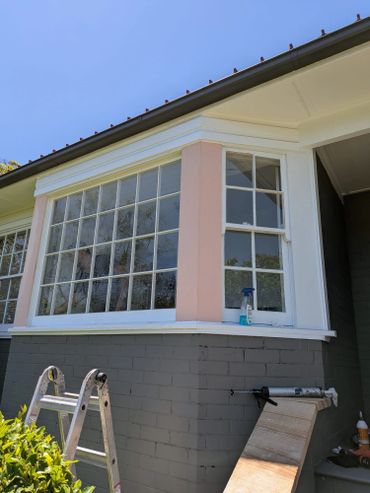 Exterior window of a house with painting and repair tools nearby.