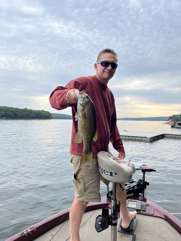 a man showing a fish standing in the boat