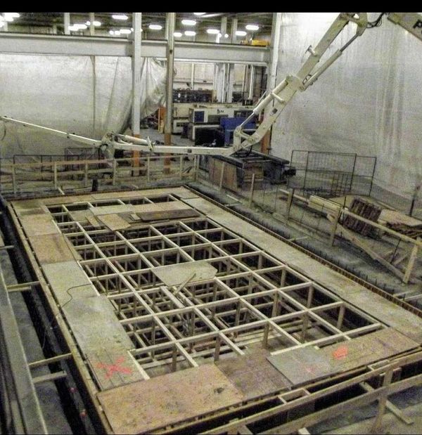 A concrete pump truck pouring concrete for a machine foundation.