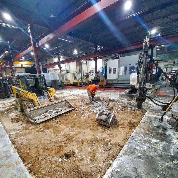 Construction workers using excavators to dig a trench for a concrete machine foundation.