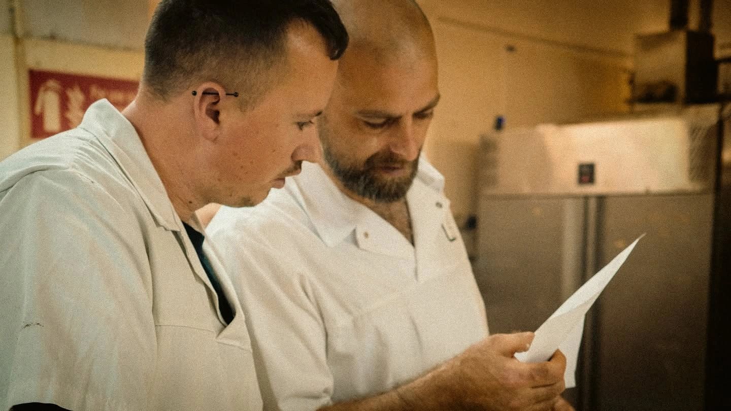 Two men examining a sheet of paper together.