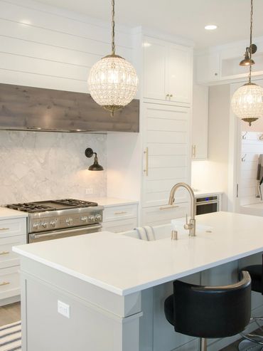 Modern white kitchen with marble backsplash and island seating.