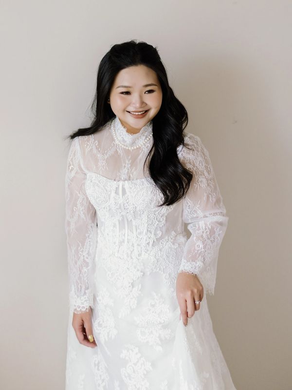 Woman in a white lace wedding dress smiling.