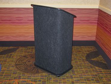 A black podium in a colorful room with patterned carpet and striped walls.
