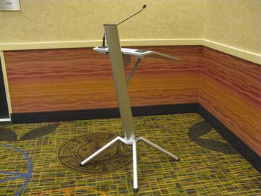 Modern podium with a microphone in an empty corner room.