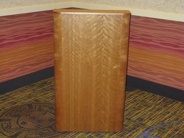 A wooden podium in a corner with colorful walls and patterned carpet.