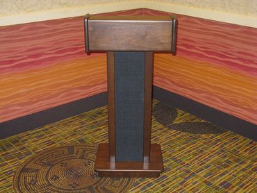 A wooden podium in a colorful room corner with patterned carpet and painted walls.