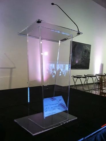 Transparent acrylic podium with a microphone on a stage.