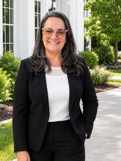 Smiling woman in business attire outdoors.