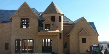 House under construction with unique turret design.