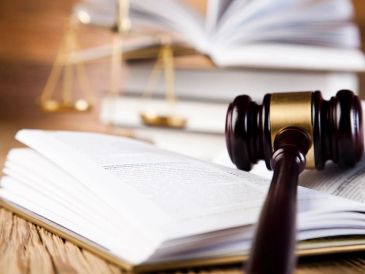 A judge's gavel resting on an open legal book with scales of justice in the background.