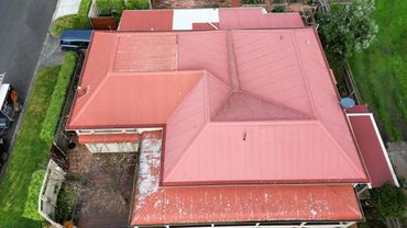 Aerial view of a house with a red roof and a small garden area.