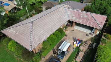A house with a tiled roof undergoing renovation work with tools and materials outside.