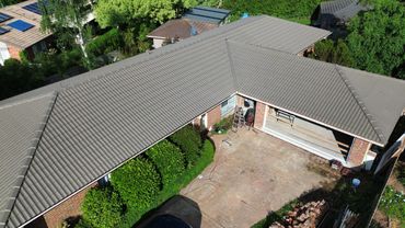 A house with a tiled roof and an open garage under renovation.