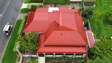 Aerial view of a house with a red roof and surrounding greenery.