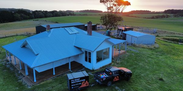 A blue-roofed house with a restoration truck parked outside at sunset.