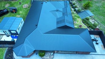 Aerial view of a house with a newly restored blue metal roof.