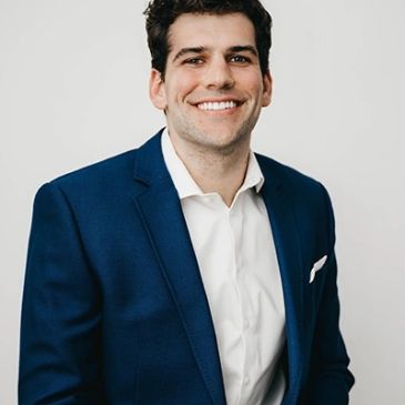Smiling man in a blue suit and white shirt.