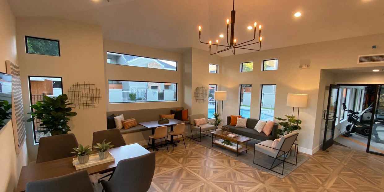 Modern living room with cozy seating, natural light, and access to a gym area.