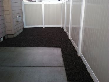 Patio con suelo de grava y cercas blancas.