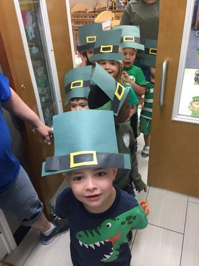 Children wearing green paper leprechaun hats lined up.